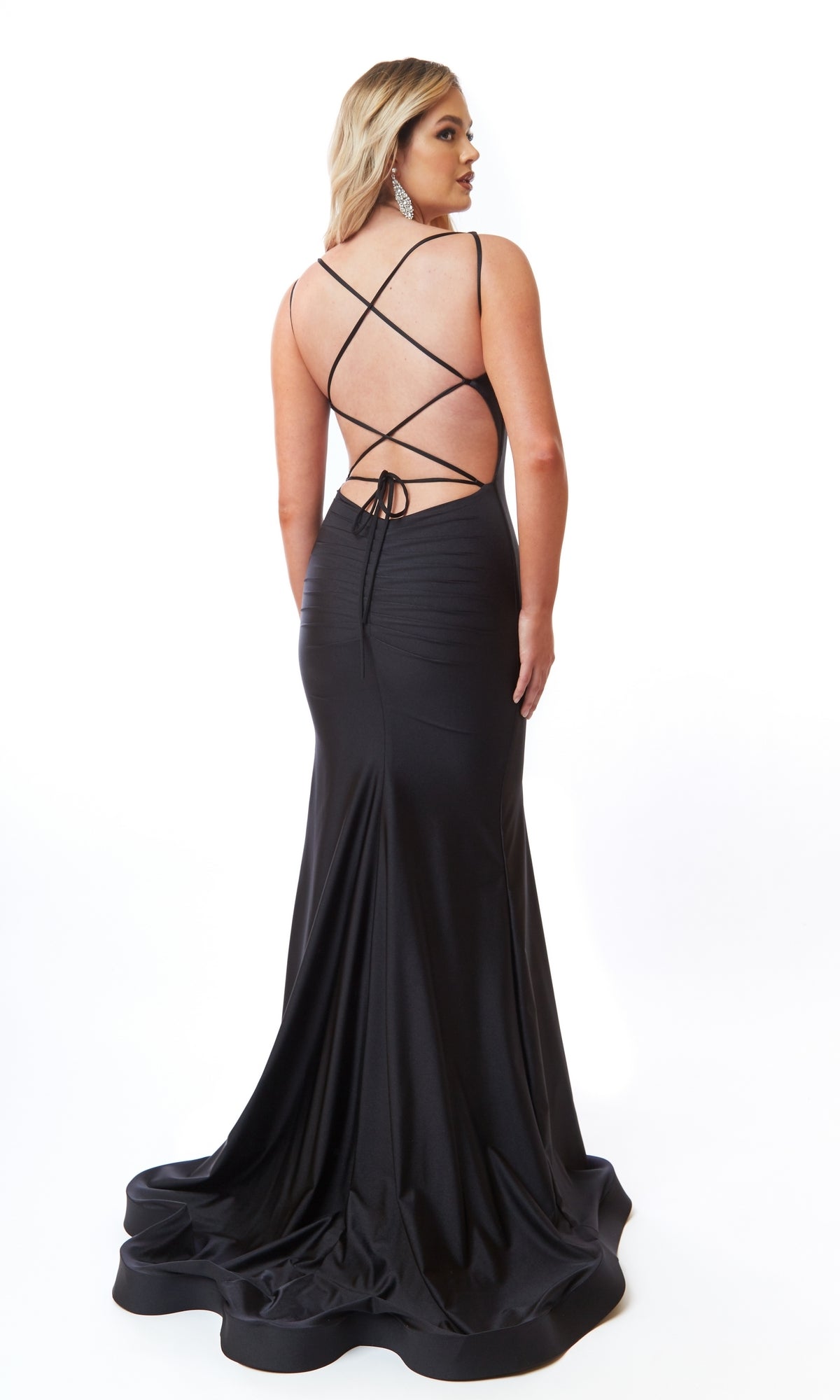 A woman poses in an elegant Square-Neck Long Prom Dress, Atria 6704H, featuring a fitted silhouette, open back, and crisscross straps, against a plain white background.